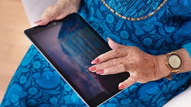 Eine Seniorin hält ein Ipad auf dem Schoss