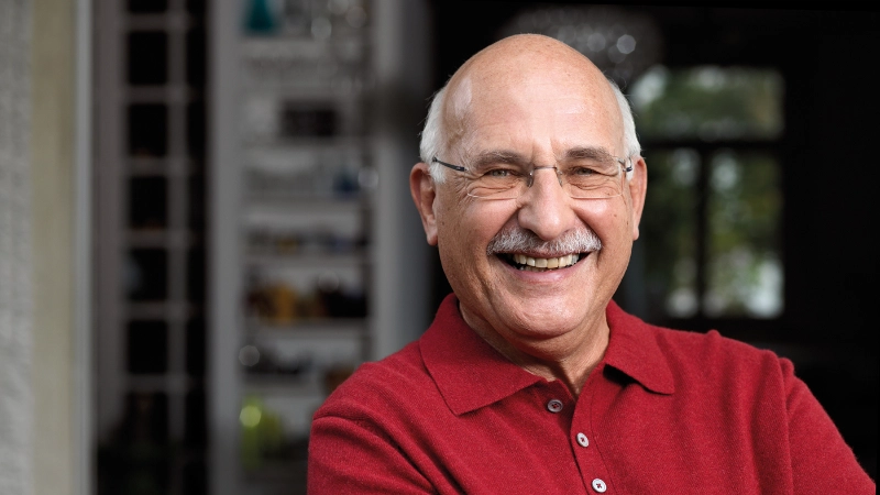 Ein Senior mit rotem T-Shirt lächelt in die Kamera