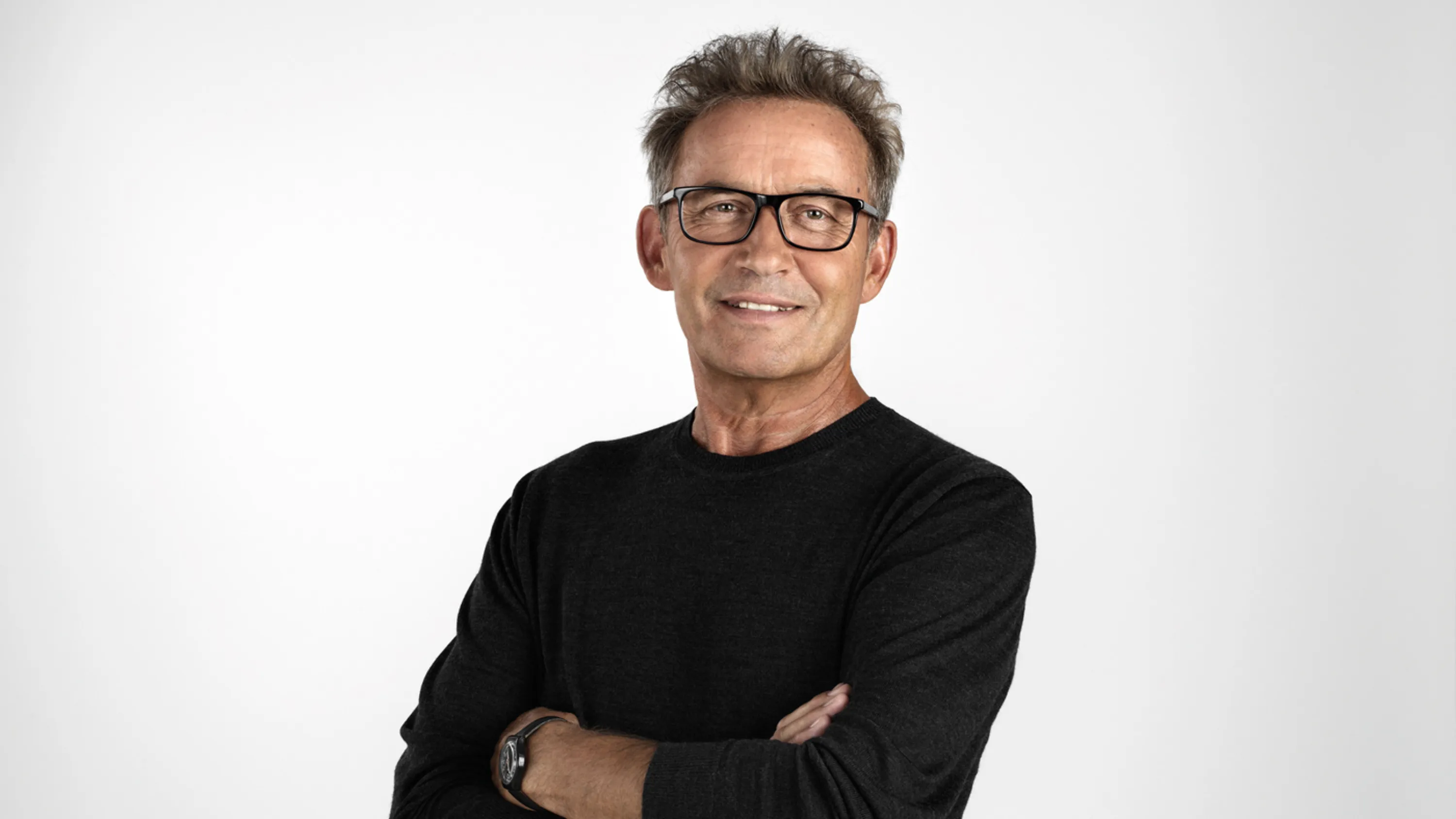 Un uomo anziano a braccia conserte sorride